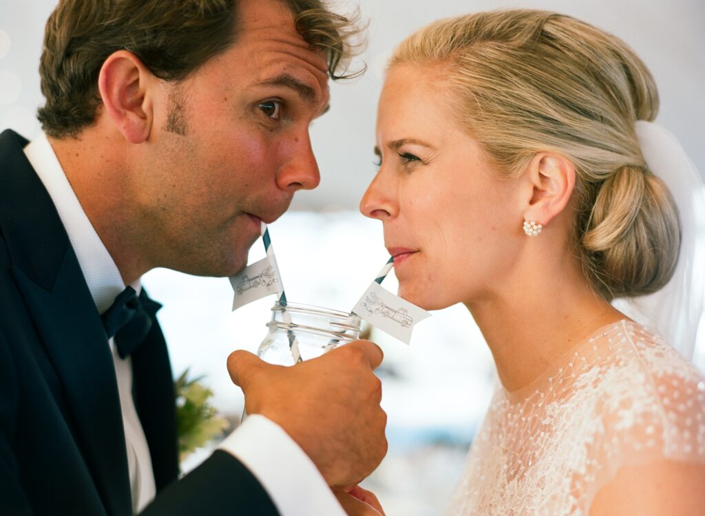 bride-and-groom-drinking-from-blue-striped-straws-out-of-a-mason-jar-on-their-wedding-day
