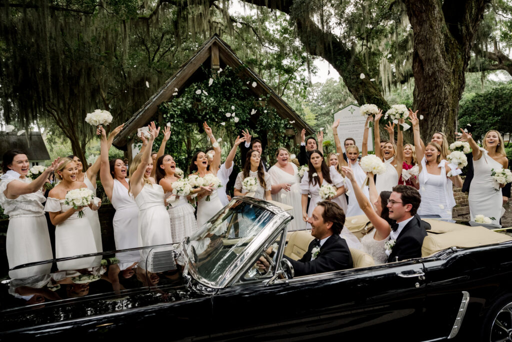 bridal-party-celebrating-couple-as-they-leave-in-chauffeured-black-convertible
