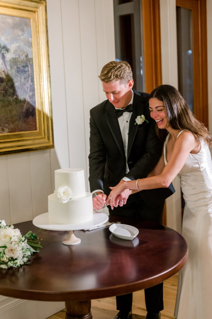 couple-laughing-as-they-cut-their-wedding-cake