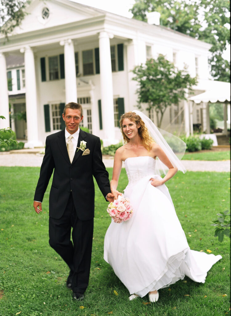 bride-and-groom-walking-in-front-of-historic-home-wedding-venue